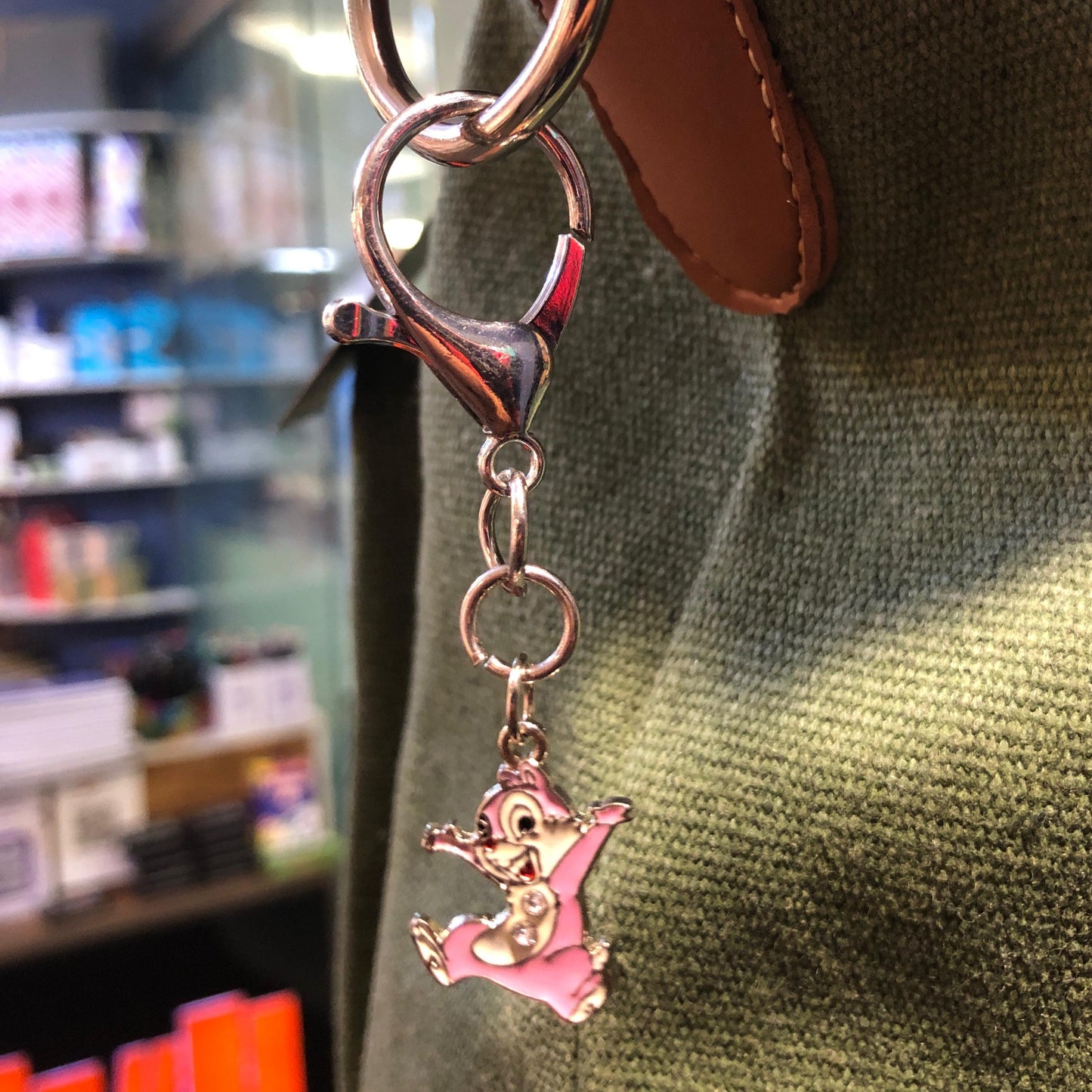 Keychain with a pink character charm attached to a brown leather strap.