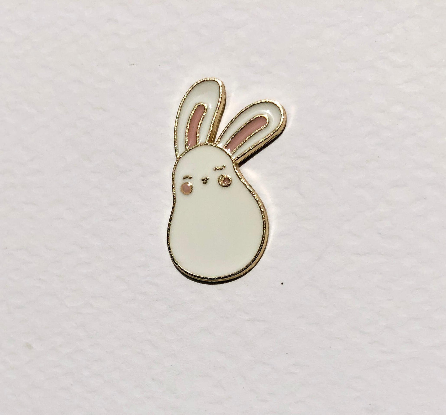Small white bunny-shaped object on a light gray background
