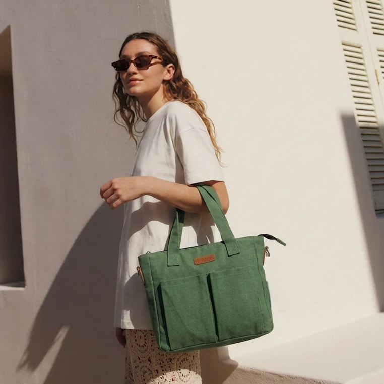Woman holding a green bag against a white wall