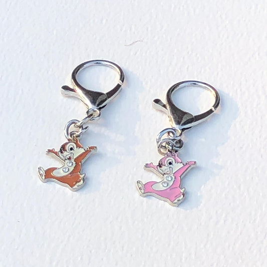 Two small charms resembling cartoon characters on a white background