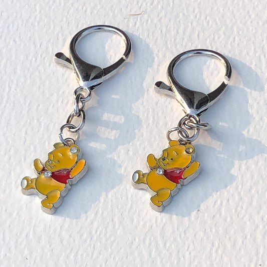 Two keychains shaped like cartoon characters with red hearts on a white background