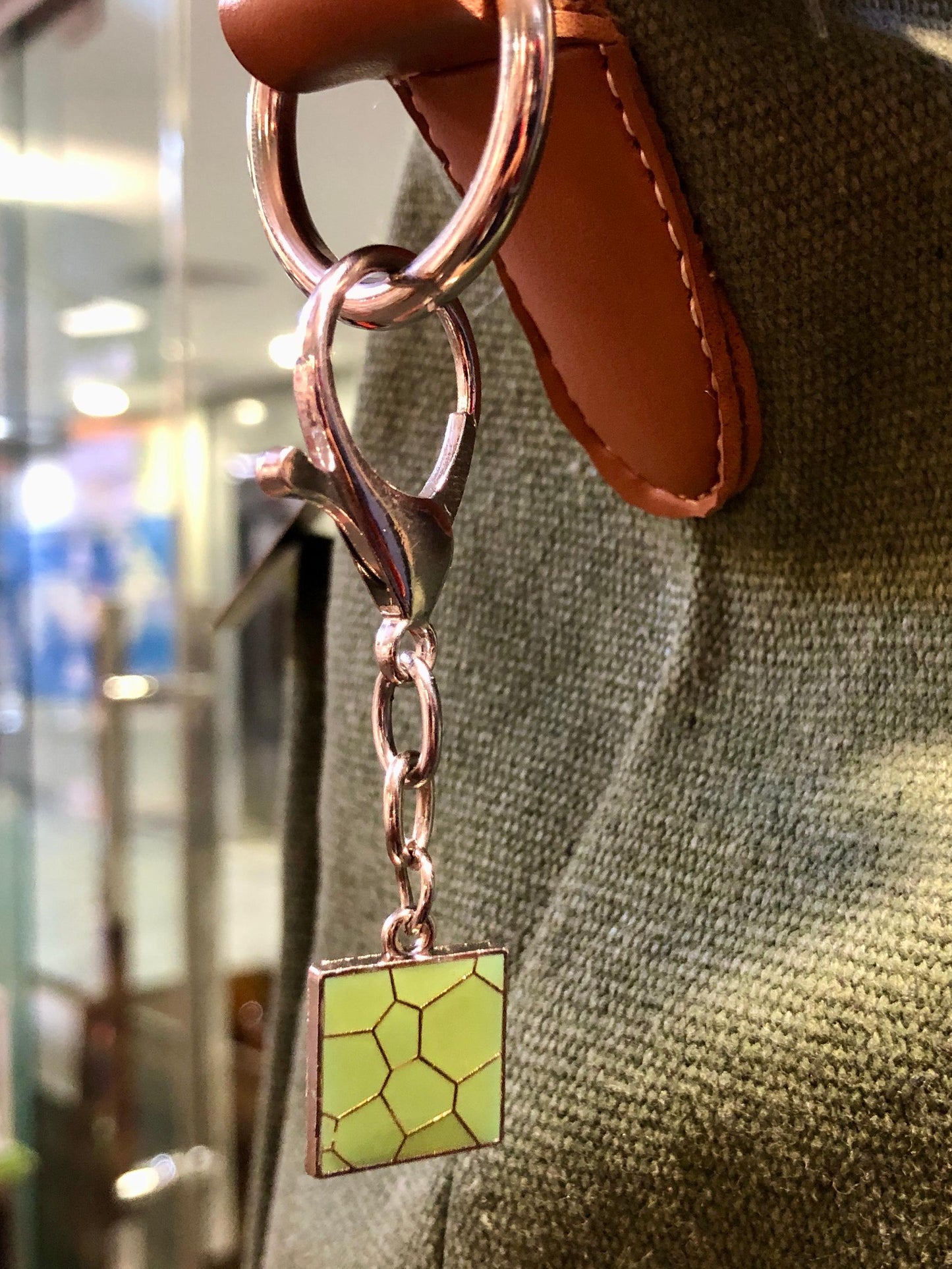 Keychain with a green square charm attached to a brown leather strap.