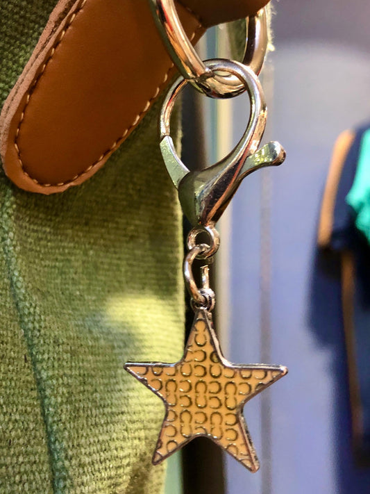 Star-shaped keychain attached to a bag with a blurred background