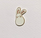 Small white bunny-shaped object on a light gray background