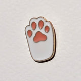 Paw print-shaped pin with red pads on a light gray background