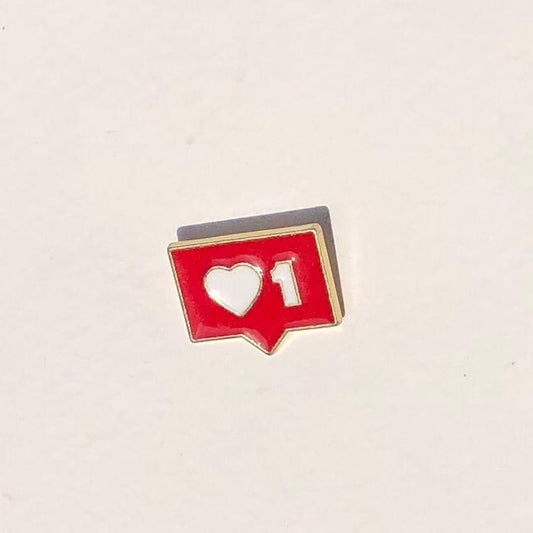 Red enamel pin with heart and number design on a beige background