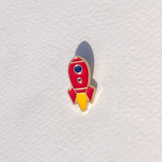 Red and yellow rocket-shaped pin on a textured white background