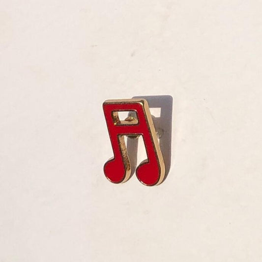 Red music note-shaped bottle opener on a beige background